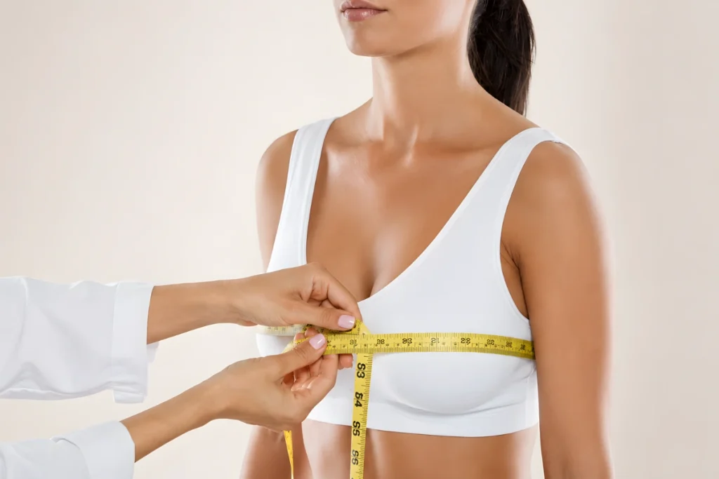 Medical professional measuring a woman’s chest with a tape measure as part of breast implant size selection.