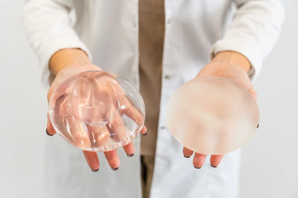Medical professional comparing two breast implants with different shapes and profiles.